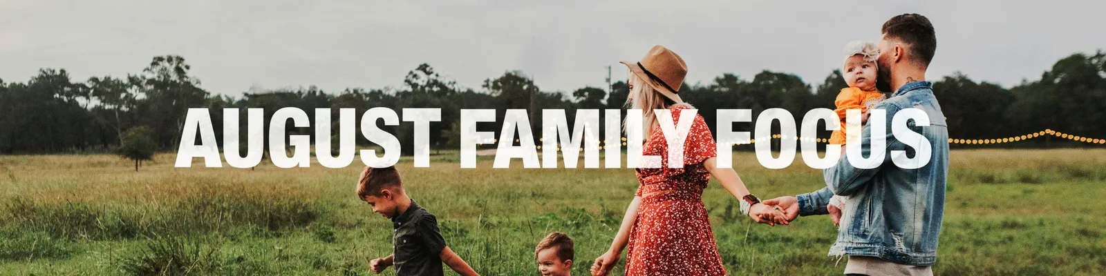 August Family Focus: a young family walking hand in hand through a field